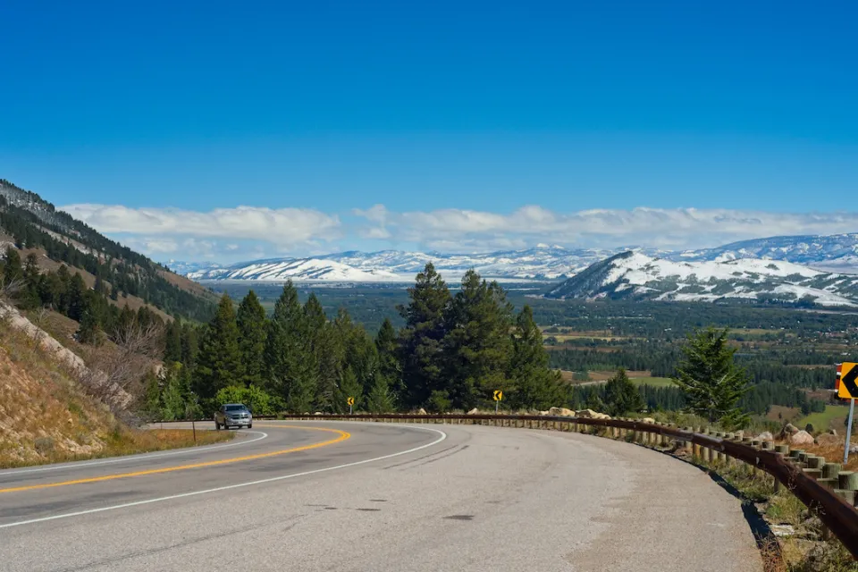 Curve in mountain highway along Teton Pass with snowy Wyoming mountains in background.